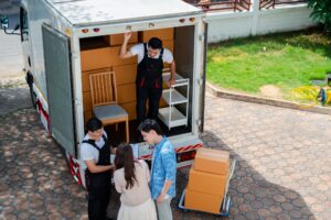 Umzugshelfer laden Möbel beim Umzug in Grevenbroich aus. Team im Gespräch mit Kunden