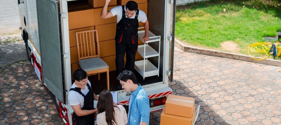 Umzugshelfer laden Möbel beim Umzug in Grevenbroich aus. Team im Gespräch mit Kunden